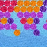 Farebné guľôčky zoradené v radoch na modrom pozadí, zahŕňajúce červené, oranžové, fialové a purpurové odtiene