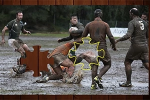 Hráči rugby hrajú na bahnistom ihrisku s chýbajúcim dielikom skladačky v popredí