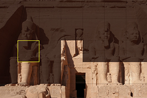 Starodávny chrám s veľkými sediacimi sochami a hieroglyfmi na kamenných stenách